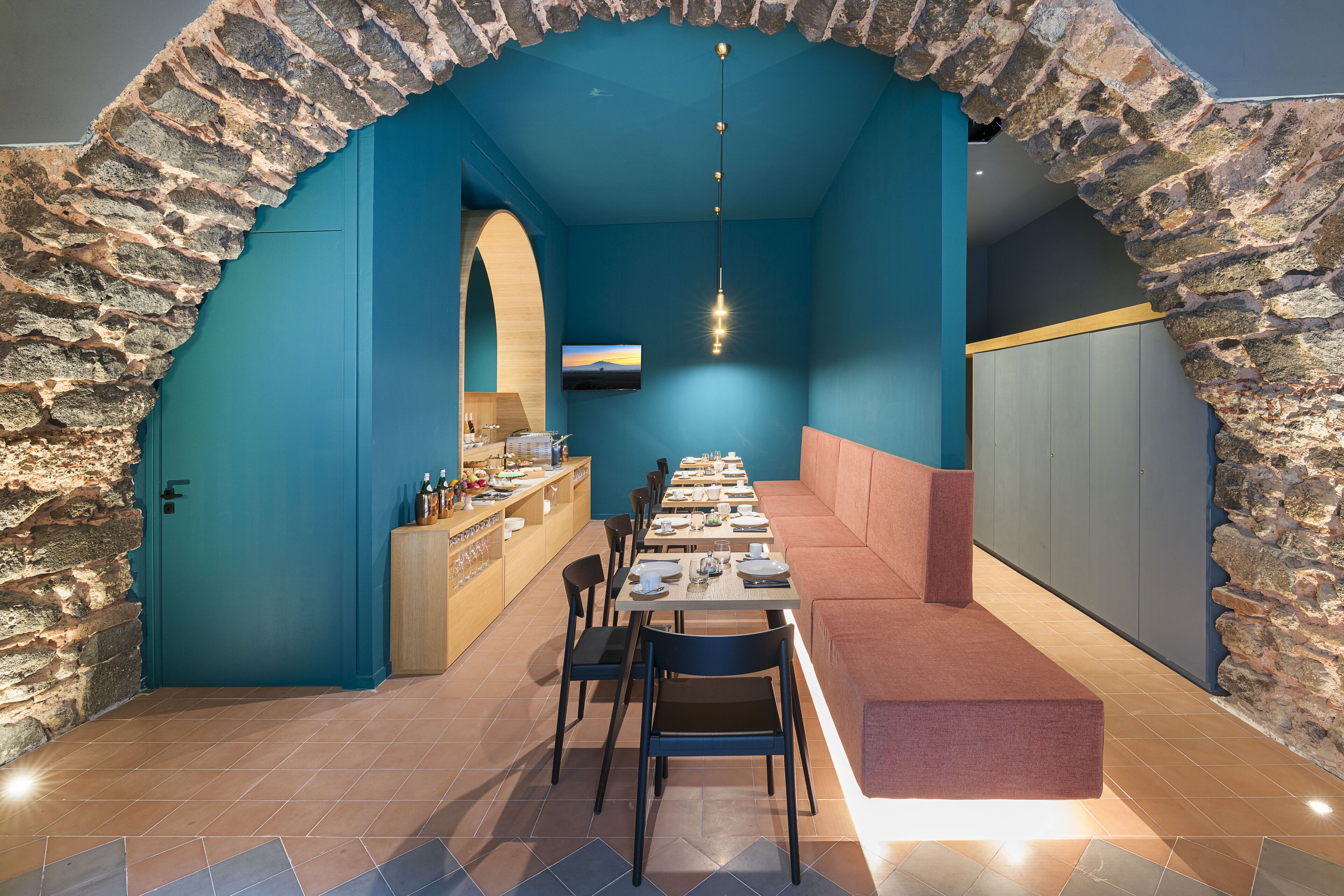 Un restaurante con un arco de piedra, paredes azules y una larga mesa dispuesta para comer.