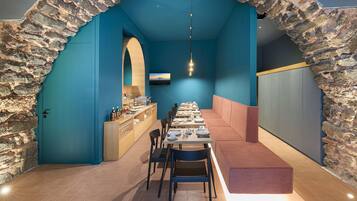Un restaurante con un arco de piedra, paredes azules y una larga mesa dispuesta para comer.