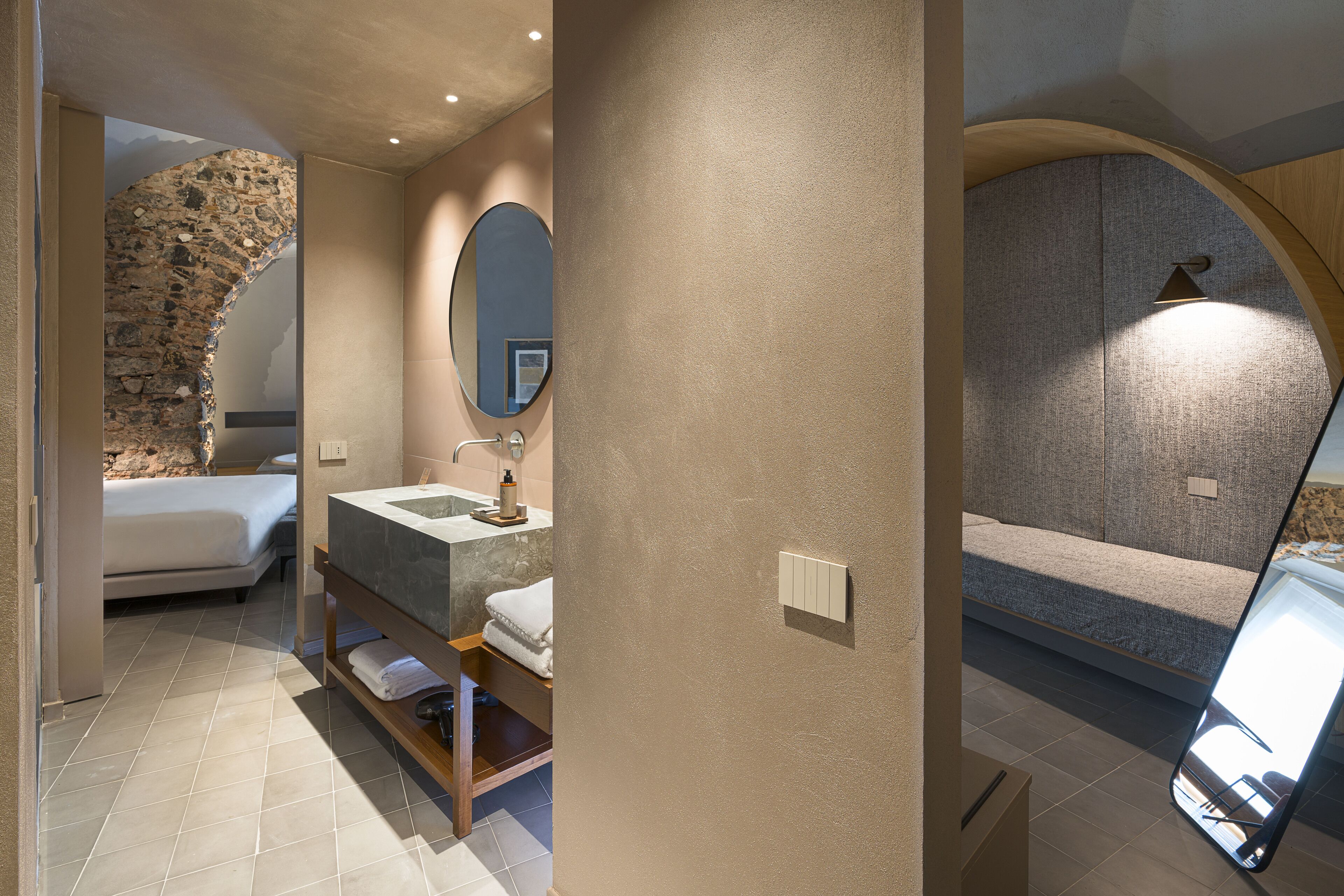 Un baño moderno con arco de piedra, un espejo grande, una bañera y un lavabo con tocador.