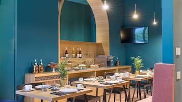 Ein Restaurant mit blauem Interieur, Holztischen und einem an der Wand montierten Fernseher.