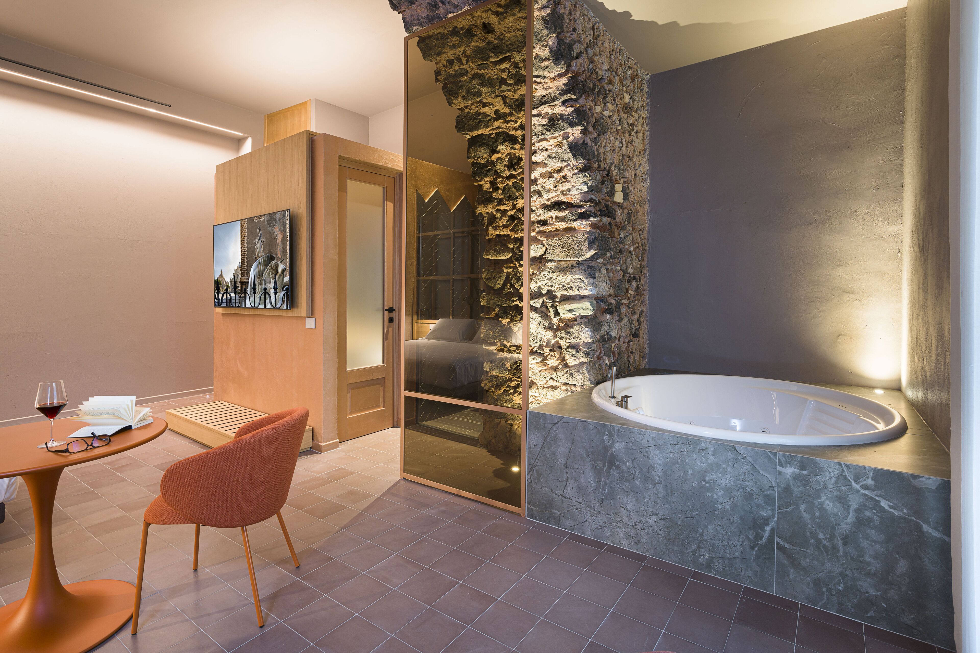 Une salle de bain moderne avec un mur d’accent en pierre, une baignoire et une douche à parois de verre.