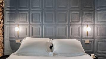 Ein Hotelzimmer mit einem grossen Bett, zwei Wandleuchten und einer Wand aus Stein.