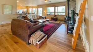 A spacious living room with a brown leather sofa, a red rug, and a fireplace. - Cascade Cabin Overlooking Lake & Golf Course (Cascade)