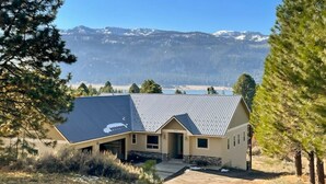 A house with a sloped roof, a stone foundation, and a view of snow-capped mountains in the background. - Cascade Cabin Overlooking Lake & Golf Course (Cascade)