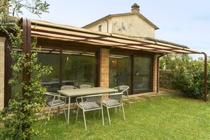 A patio with a table and chairs, a pergola, and a view of a house with a chimney. - Charming villa in the Antognolla estate (Perugia)