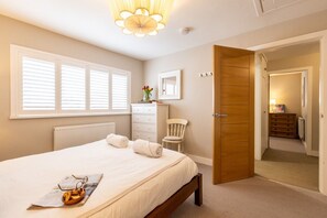 A bedroom with a bed, a dresser, a chair, and a door leading to another room. - Out of the Blue: Spacious pet-friendly holiday home in Rhosneigr (Rhosneigr)