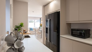 A modern kitchen with a refrigerator, microwave, and a coffee machine. - Out of the Blue: Spacious pet-friendly holiday home in Rhosneigr (Rhosneigr)
