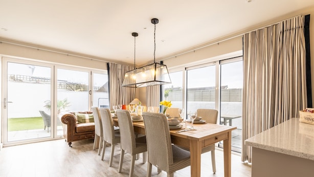 A spacious dining area with a wooden table, chairs, and a hanging light fixture. - Out of the Blue: Spacious pet-friendly holiday home in Rhosneigr (Rhosneigr)
