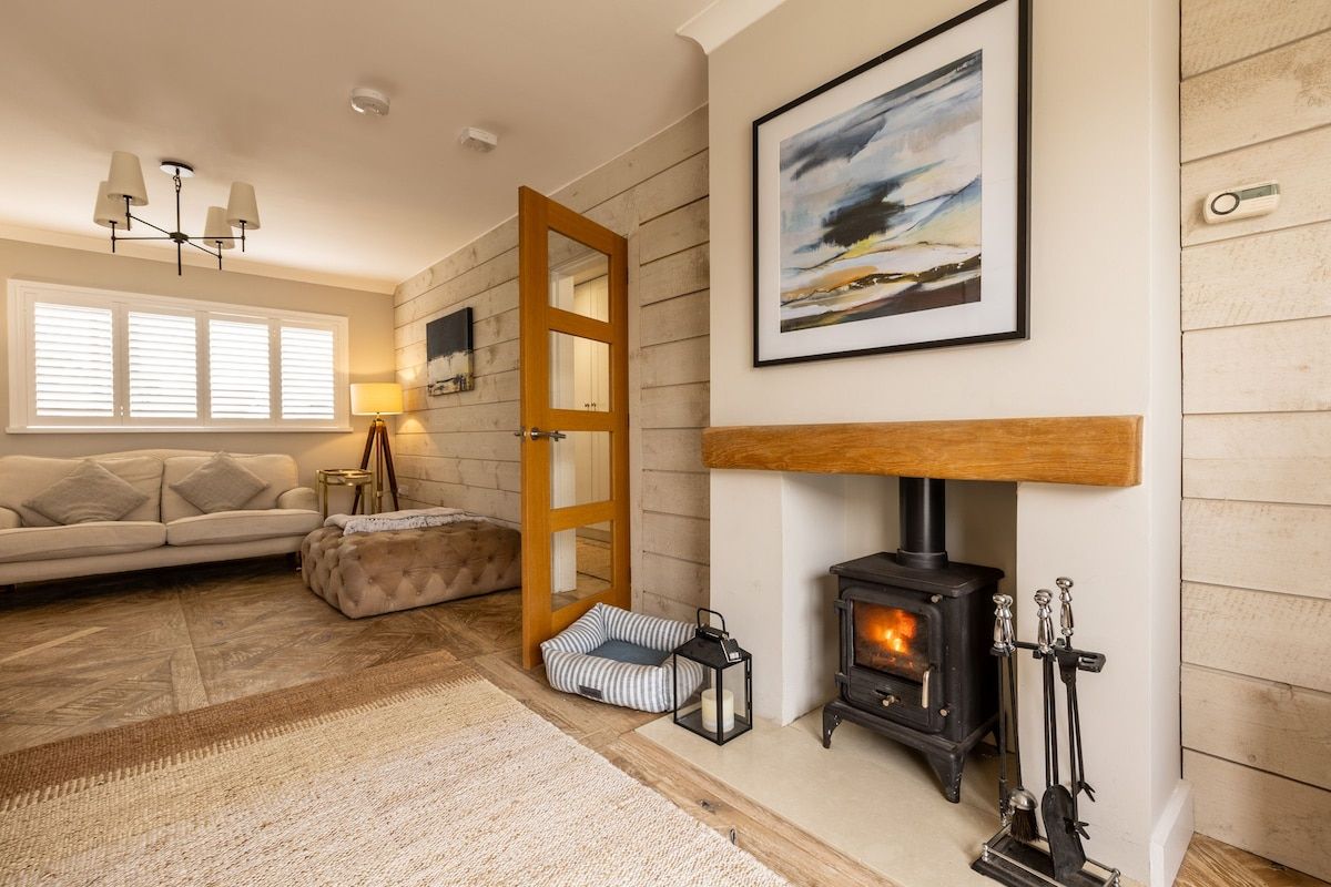 A cozy living room with a fireplace, a sofa, a rug, and a door leading to another room.