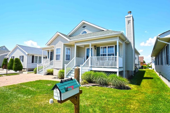 A single-story house with a front porch, a chimney, and a mailbox.