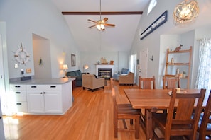 A spacious living area with a wooden dining table, sofas, and a fireplace.