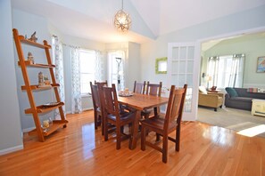 A dining area with a wooden table and chairs, a wooden ladder shelf, and a chandelier.