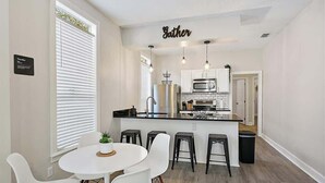 Una cucina moderna con isola centrale, mobili bianchi e illuminazione a sospensione.