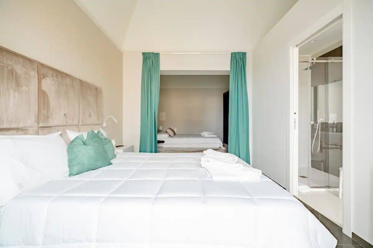A hotel room with a large bed, a wardrobe, and a bathroom with a glass shower.