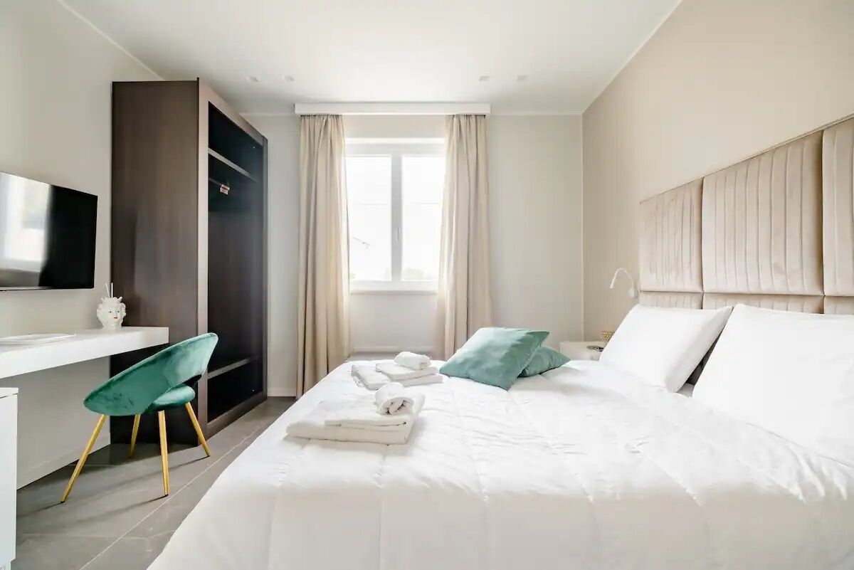 Una habitación de hotel moderna con una cama, un escritorio, una silla, un armario y un televisor.