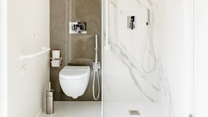 A modern bathroom with a glass shower enclosure, a white toilet, and a marble wall. - SHoruq (Marsala)