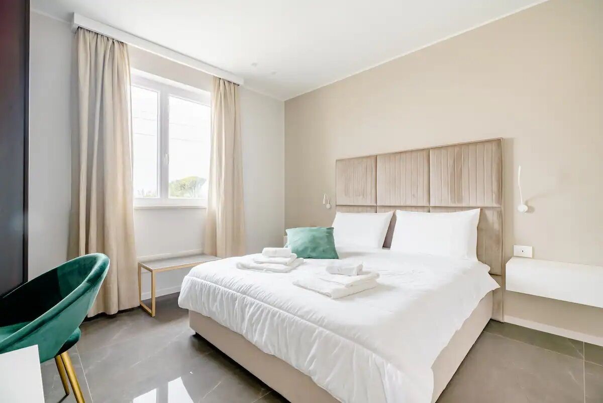 Een moderne hotelkamer met een groot bed, een nachtkastje, een stoel en een raam met gordijnen.