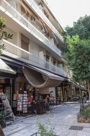 A multi-story building with balconies, outdoor seating, and a variety of shops on the ground floor. - Deluxe Apt. in the Heart of Kolonaki (Athens)