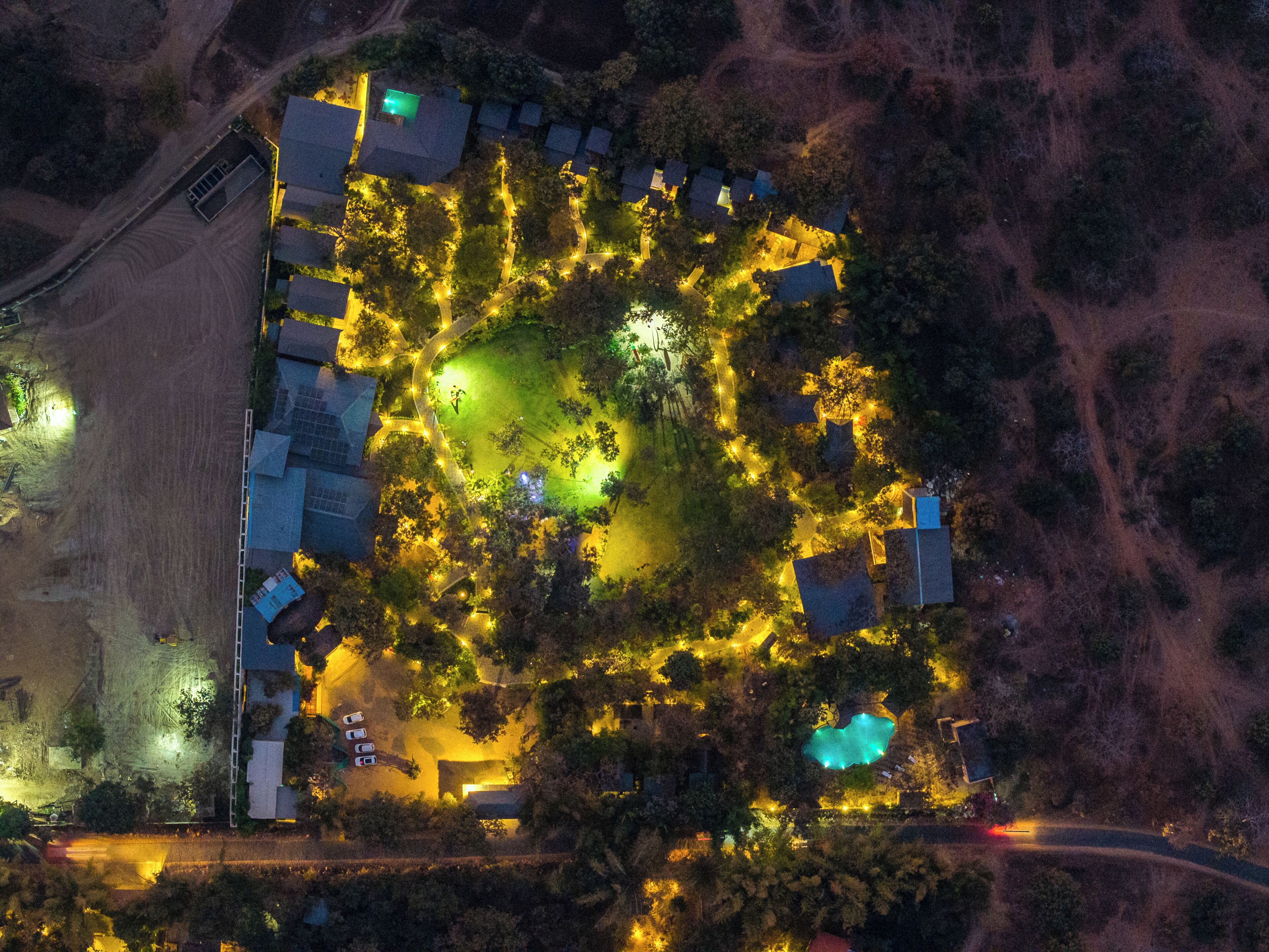 An aerial view of a residential area with houses, a swimming pool, and a road.