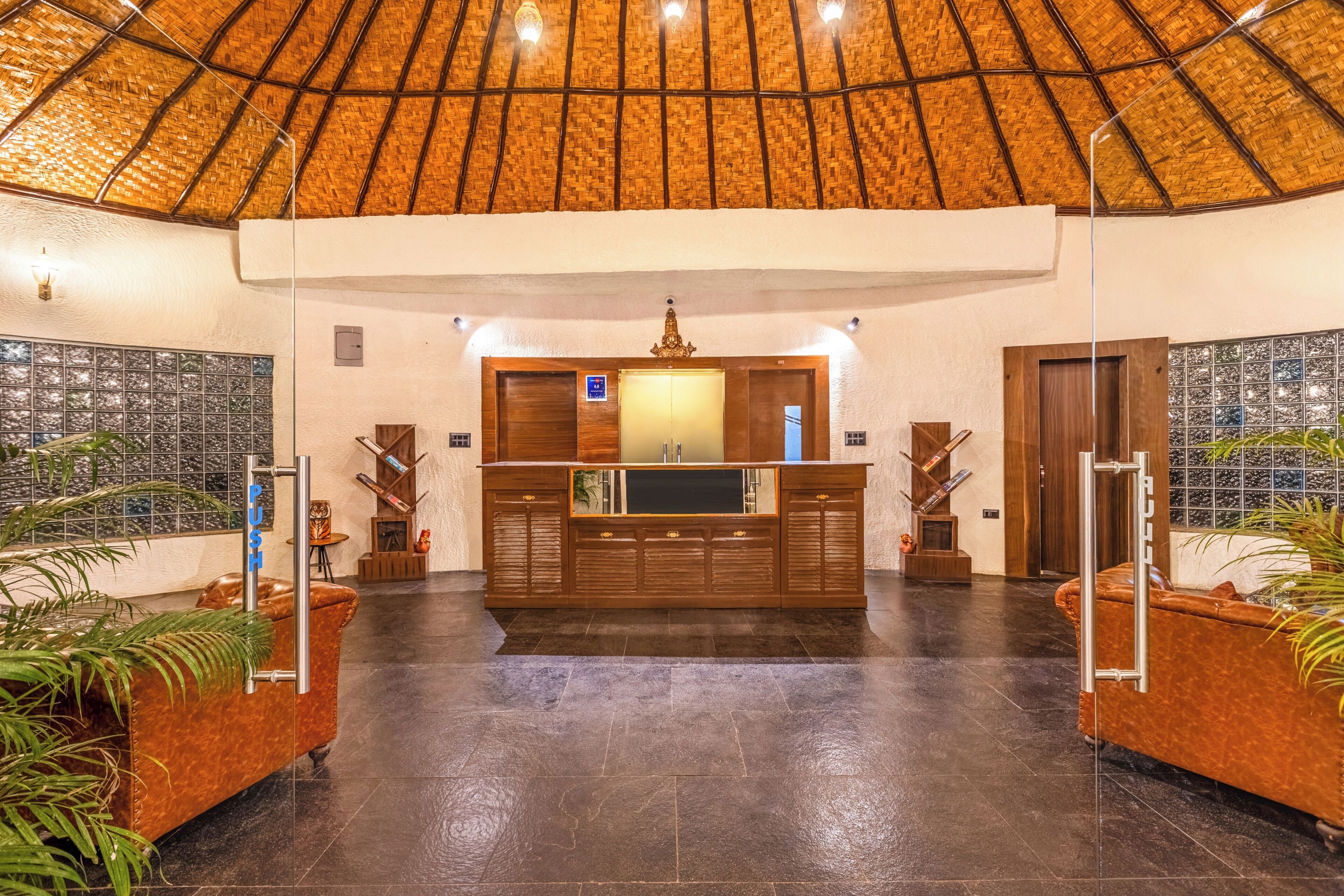 A reception area with a wooden reception desk, a large glass window, and a thatched roof ceiling.