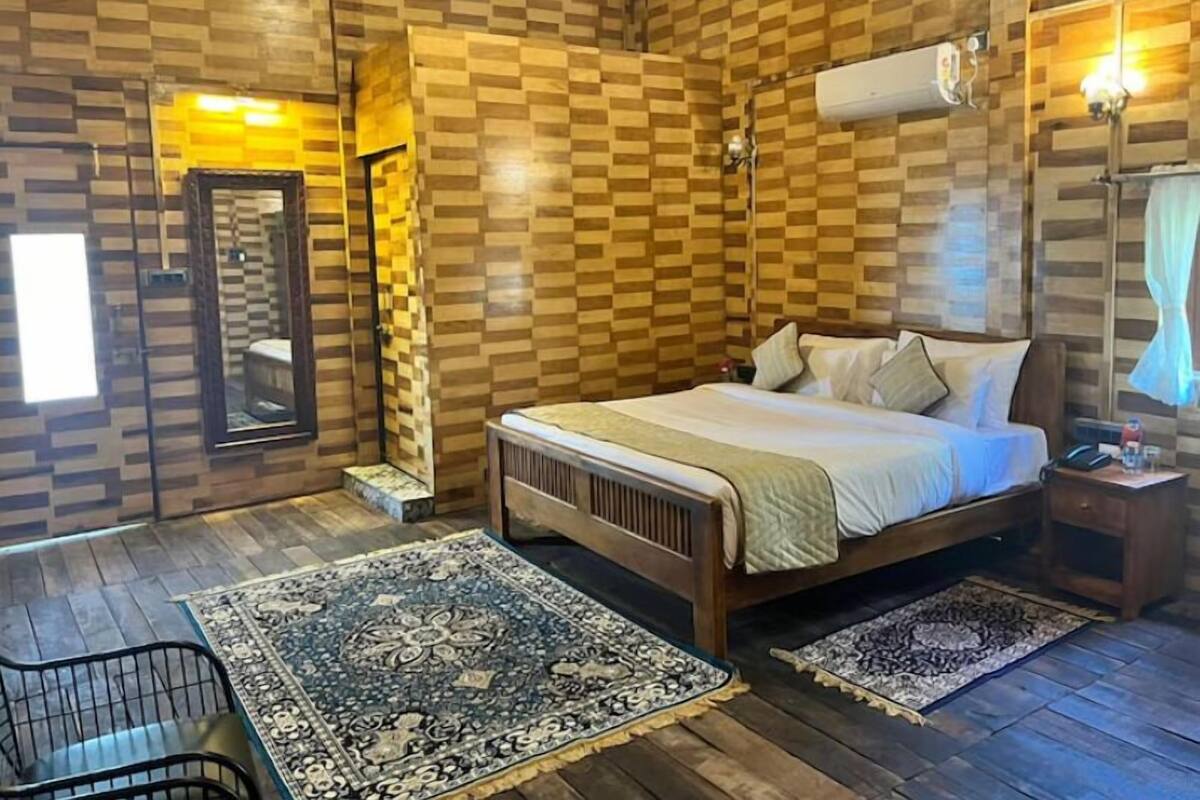 A bedroom with a wooden checkered wall, a bed with pillows, a nightstand, a chair, and two patterned rugs.