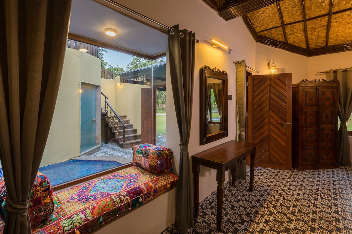 A room with a bench by a window, a wooden door, and a staircase leading outside.