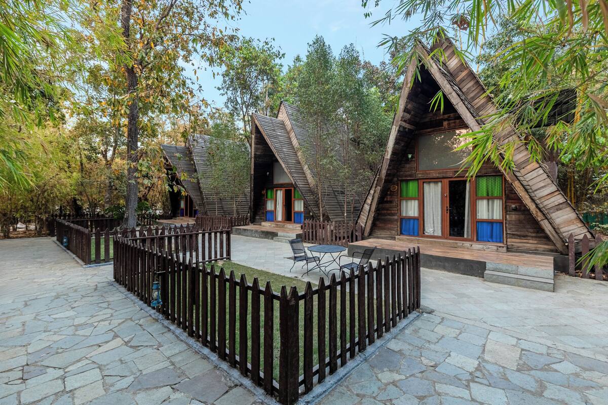 A courtyard with wooden A-frame structures, stone flooring, and a wooden fence.