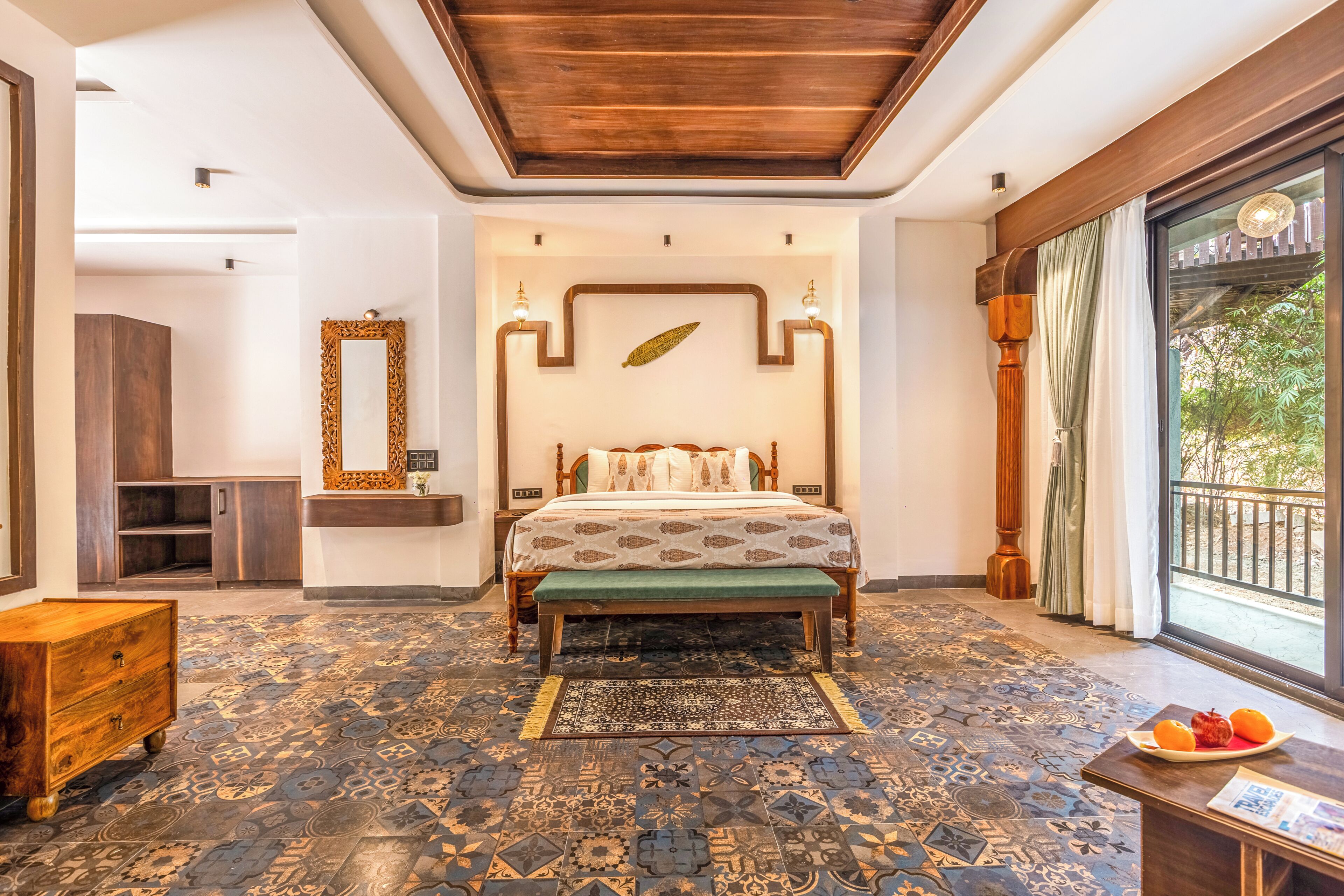 Een slaapkamer met een bed, een houten dressoir, een spiegel en een raam met uitzicht.