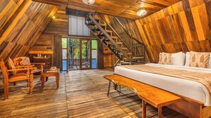 Interior de madera con cama, banca y escalera.