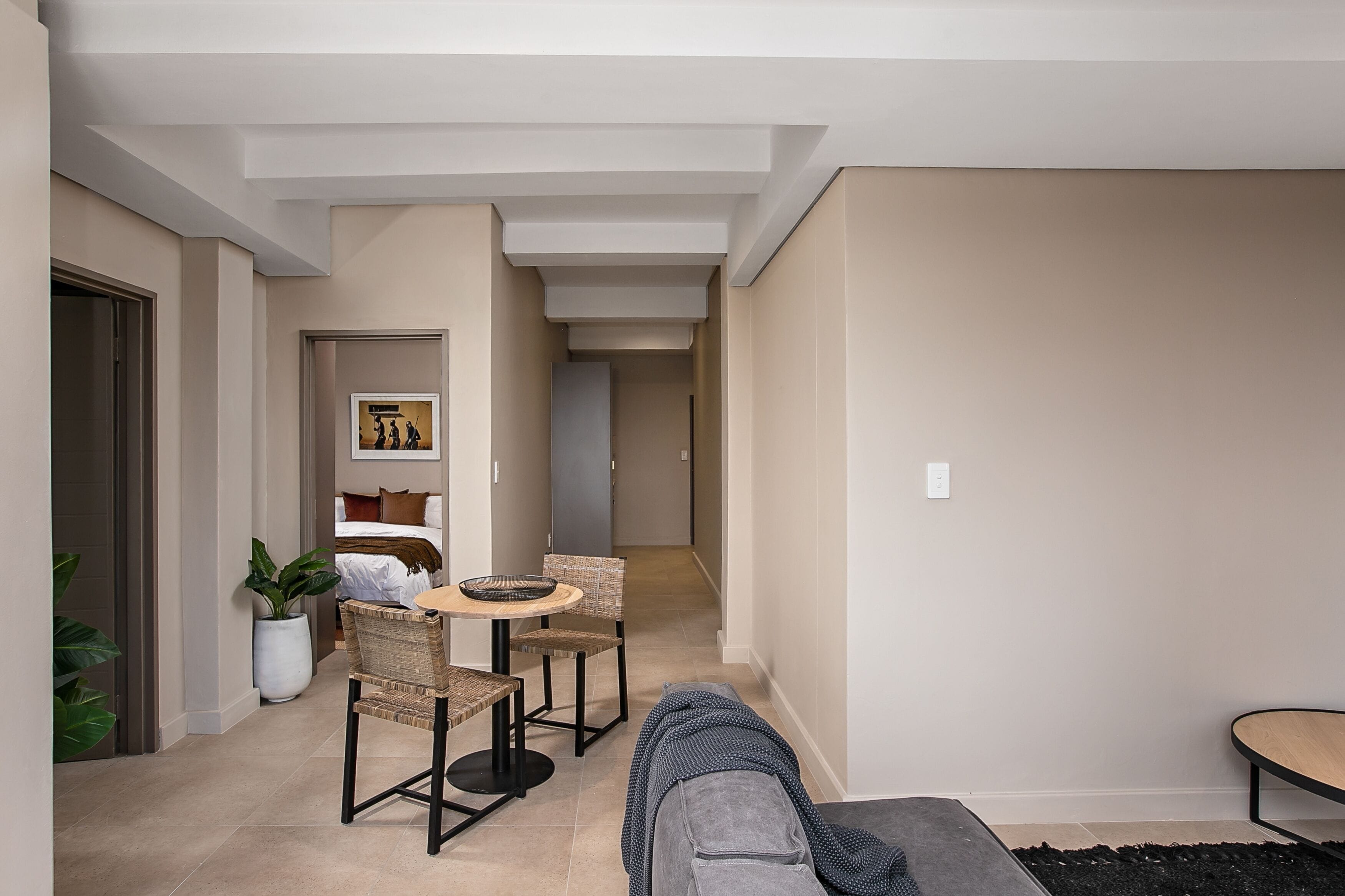 A modern interior with a dining area, a sofa, and a bed in the background.