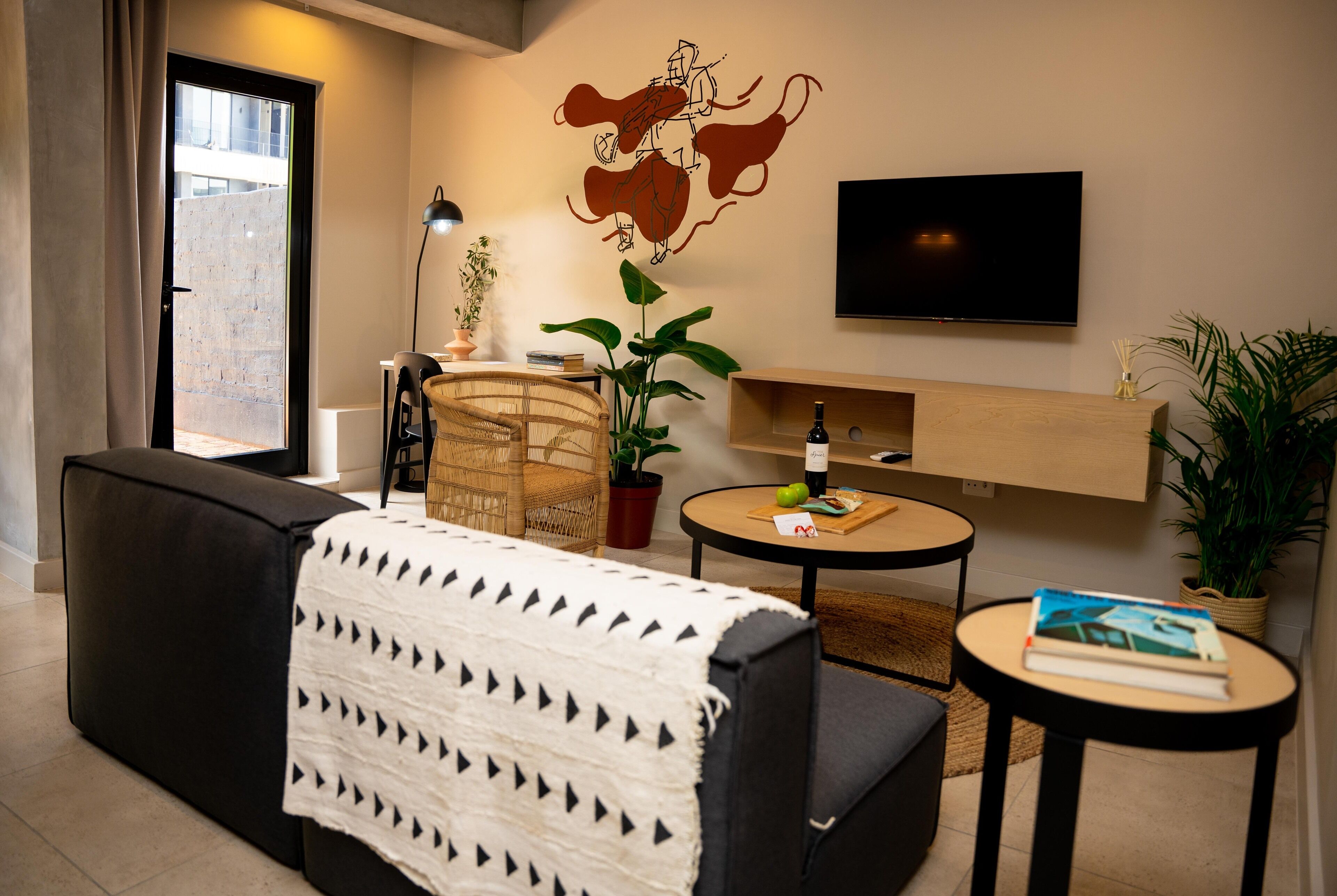Een moderne woonkamer met een bank, een salontafel, een televisie en een wandplank met een plant.