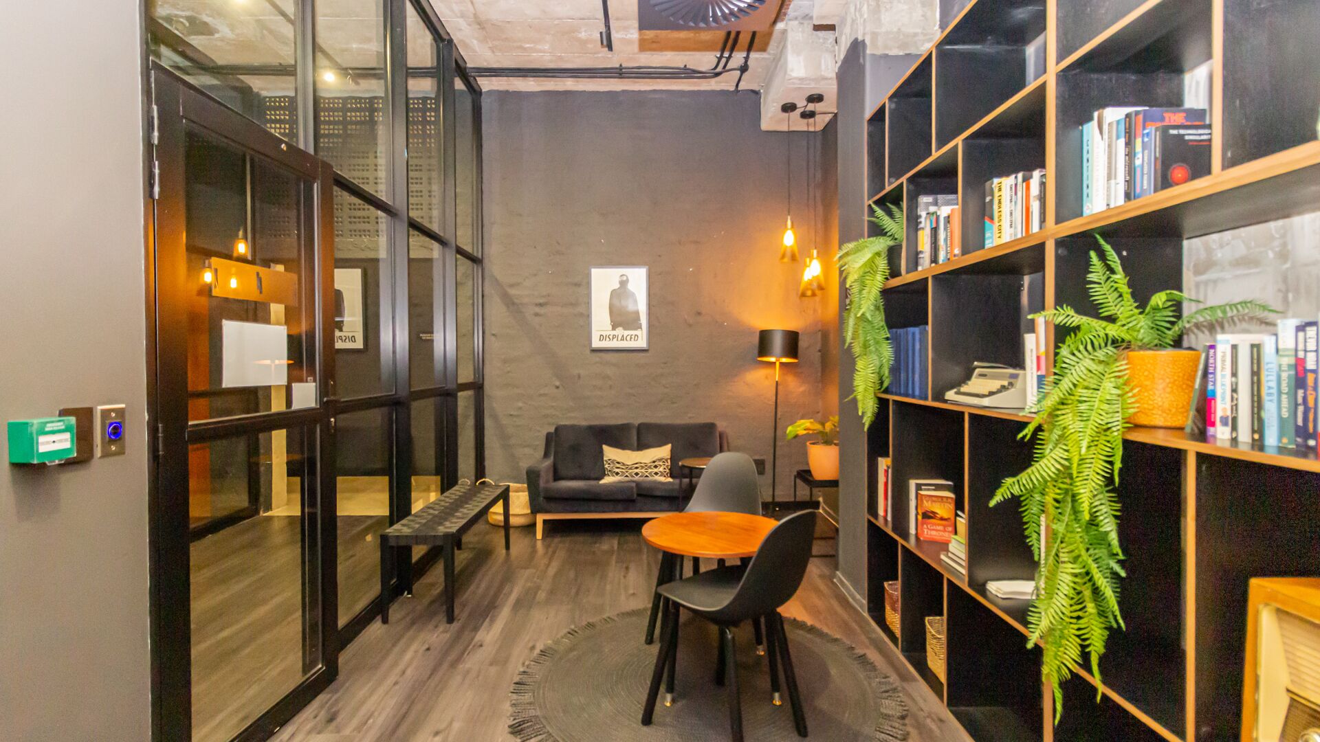 Un espacio lounge moderno con un sofá, una mesita y una estantería llena de libros.
