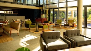 Eine geräumige Lobby mit moderner Einrichtung, großen Fenstern und Blick auf Grünflächen.