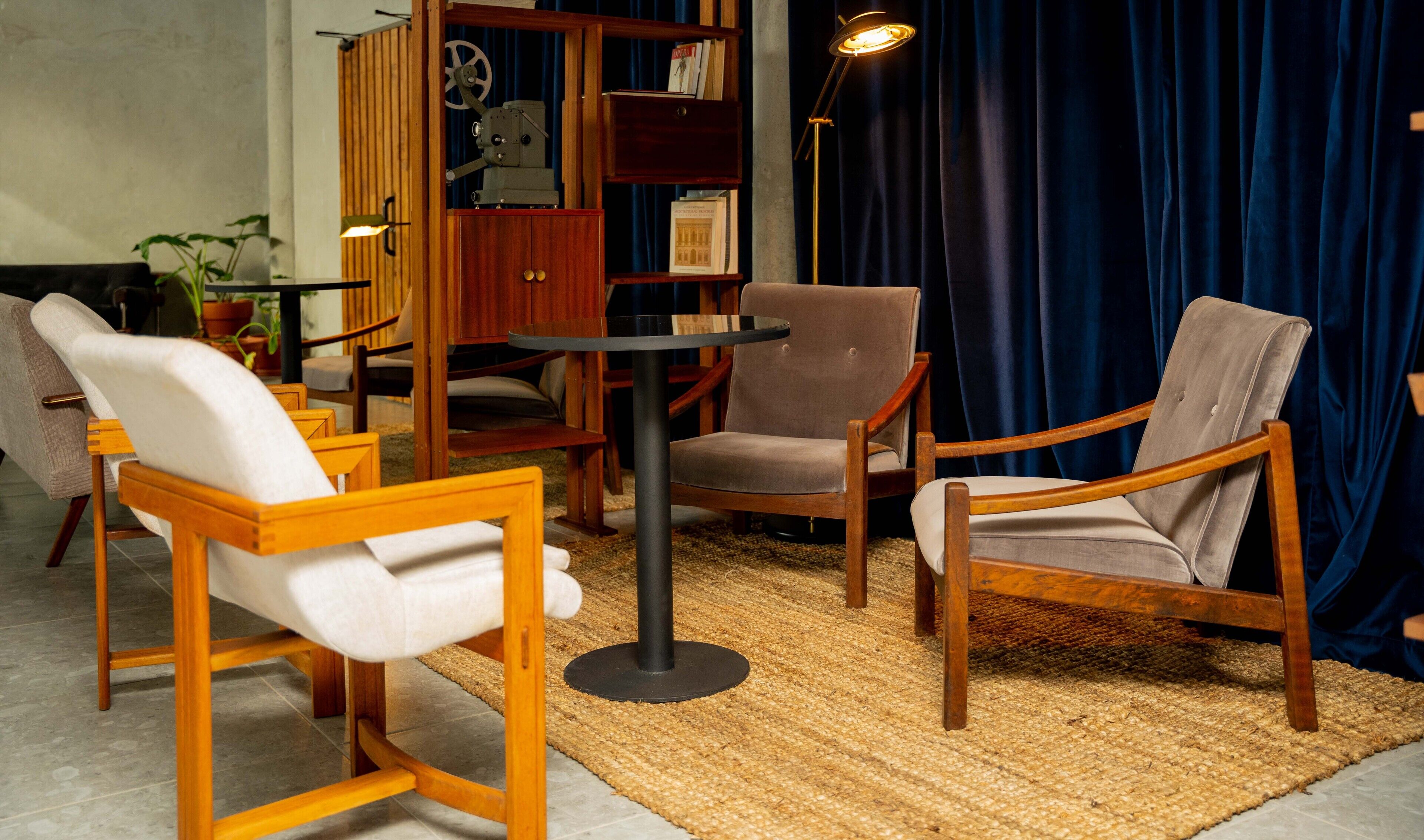 A room with a wooden bookshelf, a round table, and two armchairs.