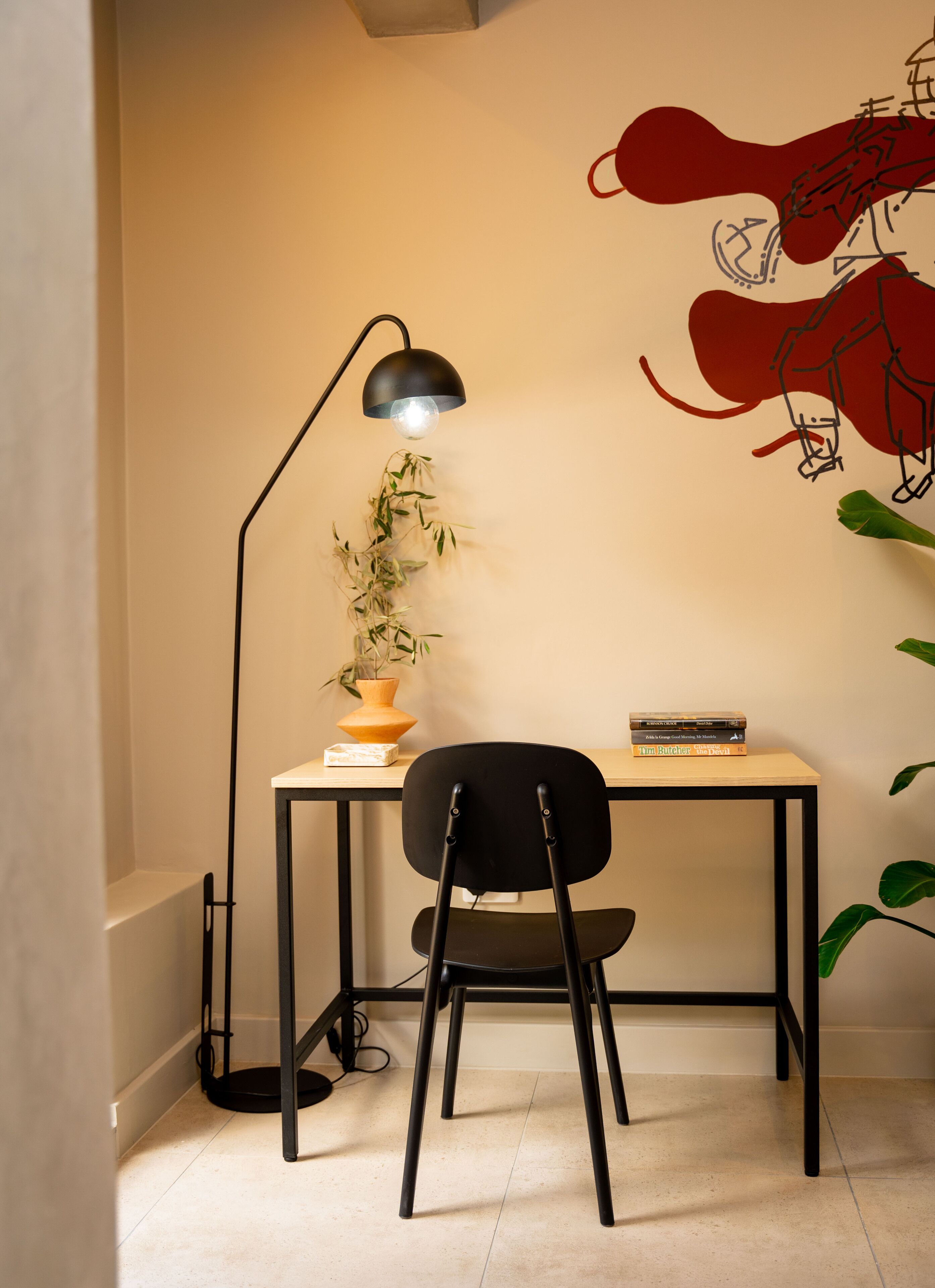 Une pièce d’angle comprenant un bureau, une chaise, une lampe et des œuvres d’art murales.
