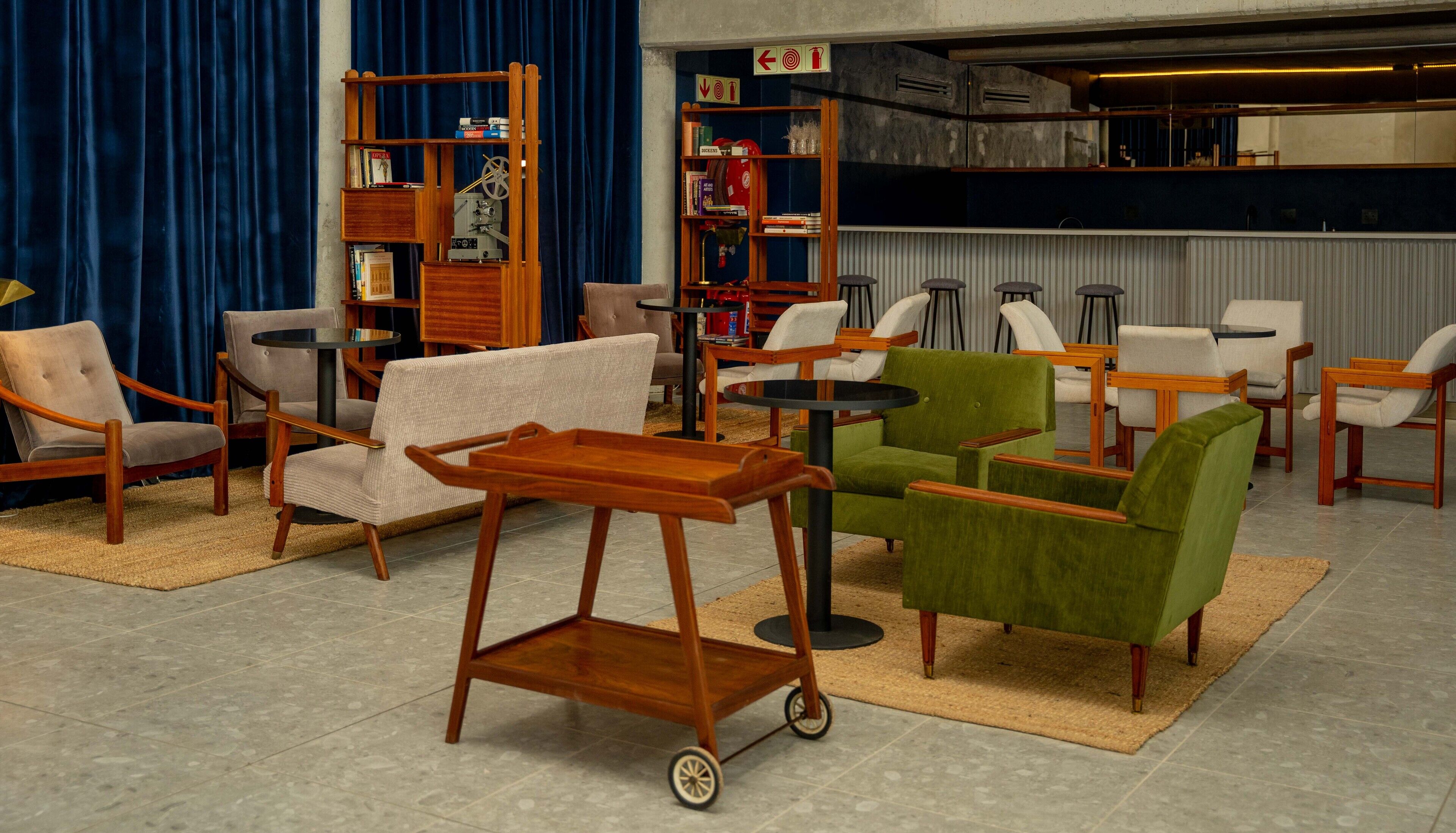 A modern living room with a variety of seating options, including armchairs and sofas, a wooden coffee table, and a small cart.