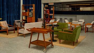 A modern living room with a variety of seating options, including armchairs and sofas, a wooden coffee table, and a small cart.