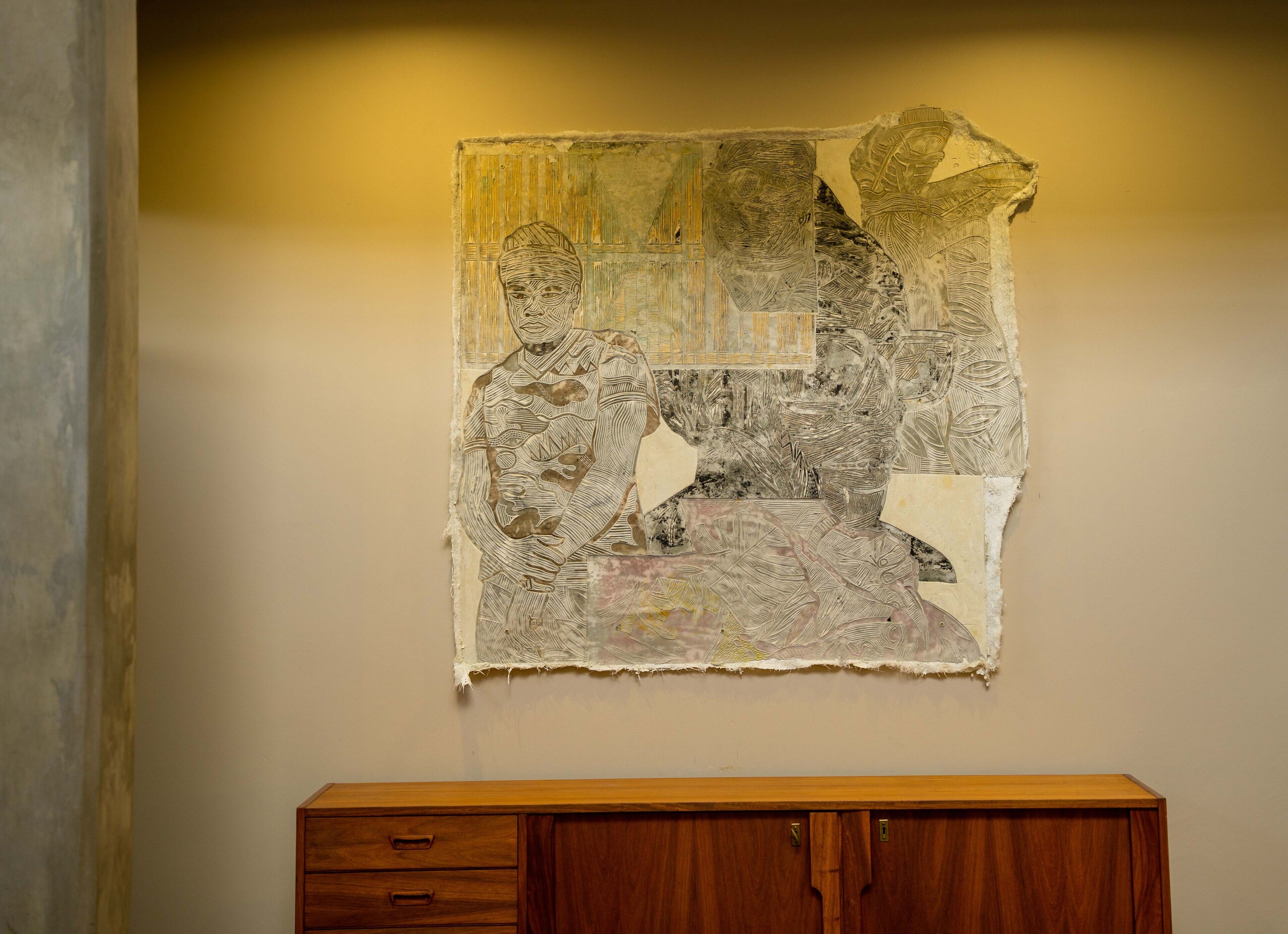 A wall-mounted artwork with a torn section revealing a patterned design underneath.