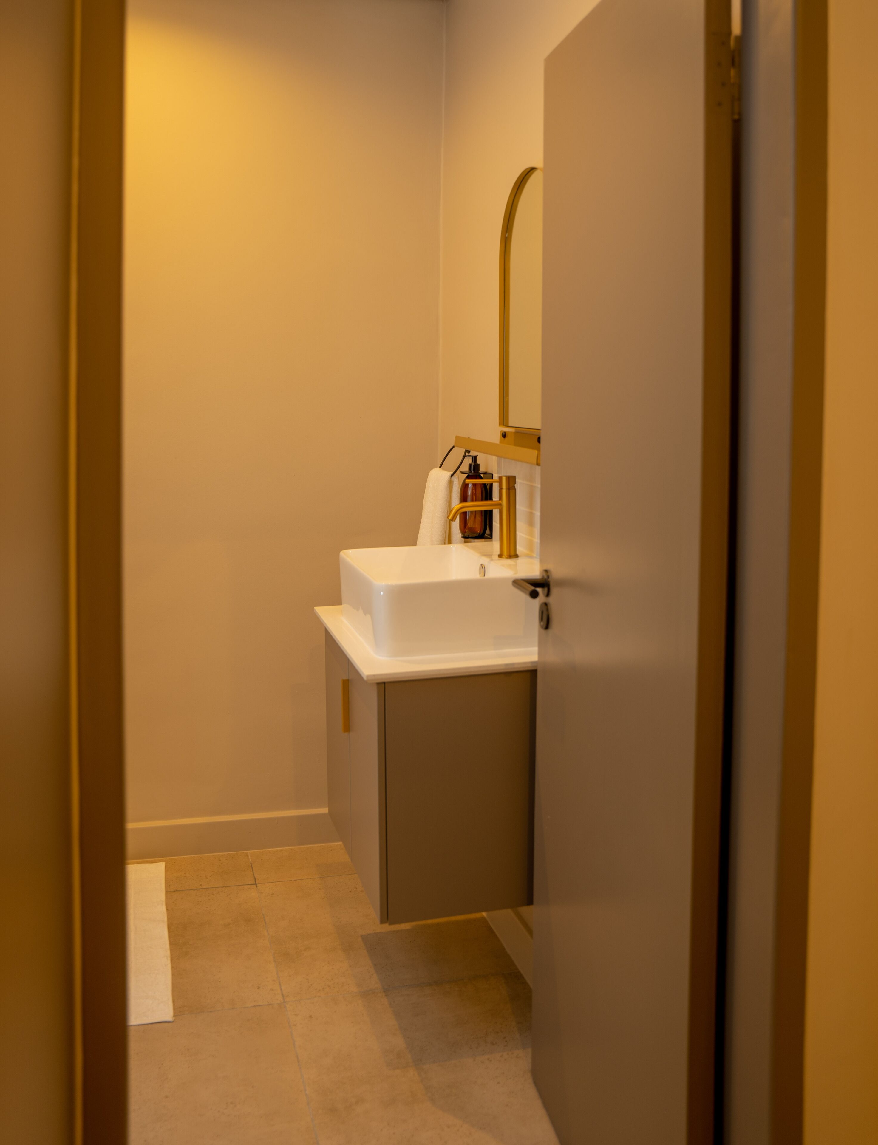 A small bathroom with a white sink, a mirror, and a towel hanging on the wall.