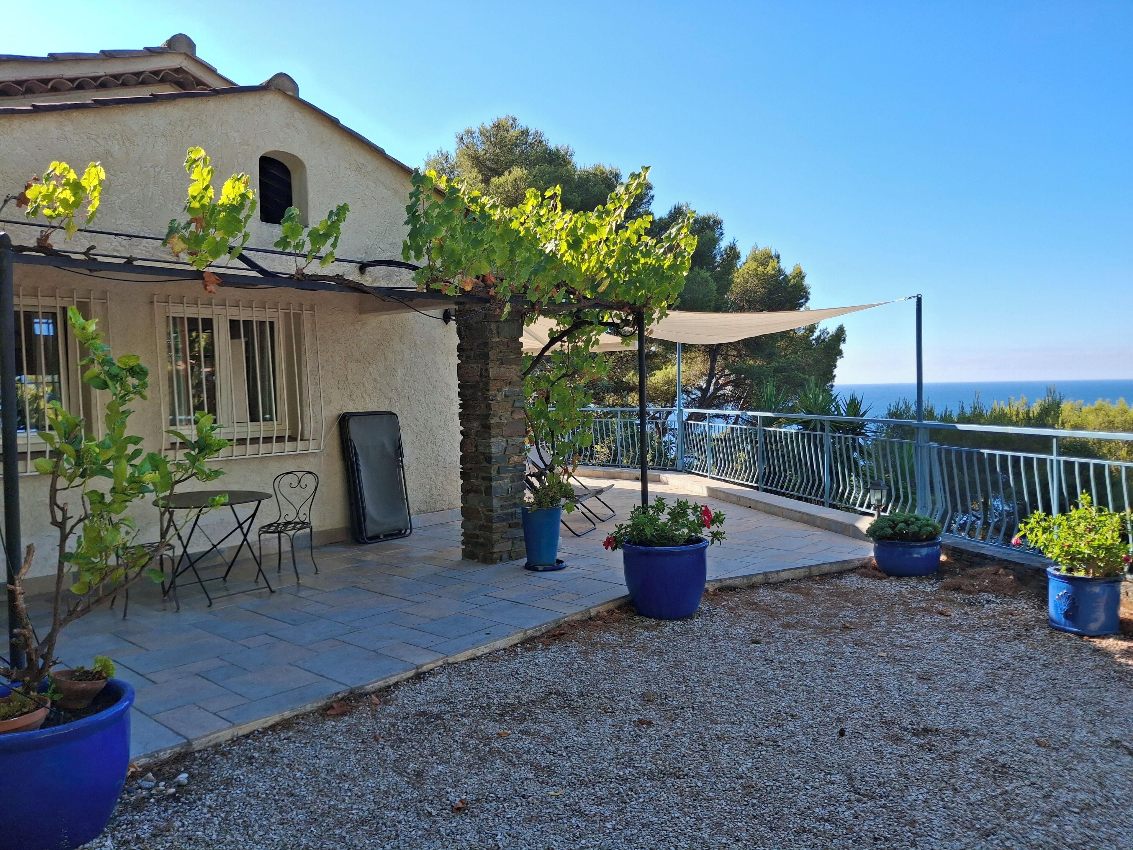 A terrace with potted plants, a table, and chairs.