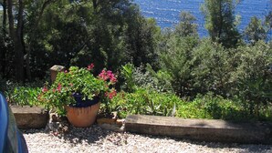 Un jardin offrant une vue sur la mer, entouré d’arbres et agrémenté de plantes en pot.