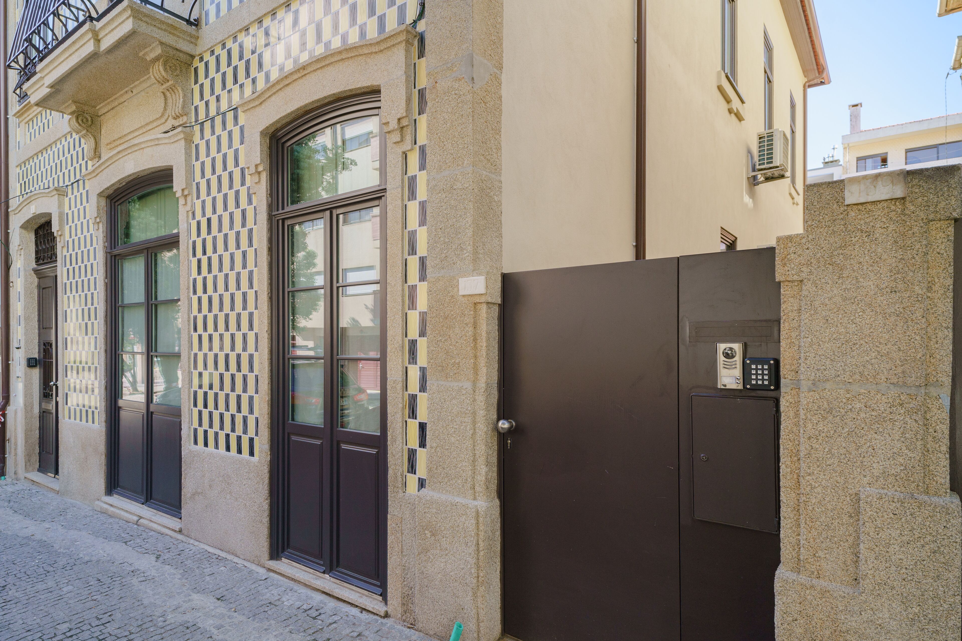 A building with a checkered facade, large arched windows, and a modern security gate.