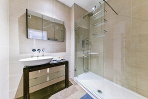 A modern bathroom with a glass-enclosed shower, a white sink, and a mirror above the vanity. - South-Kensington Apartment (London)