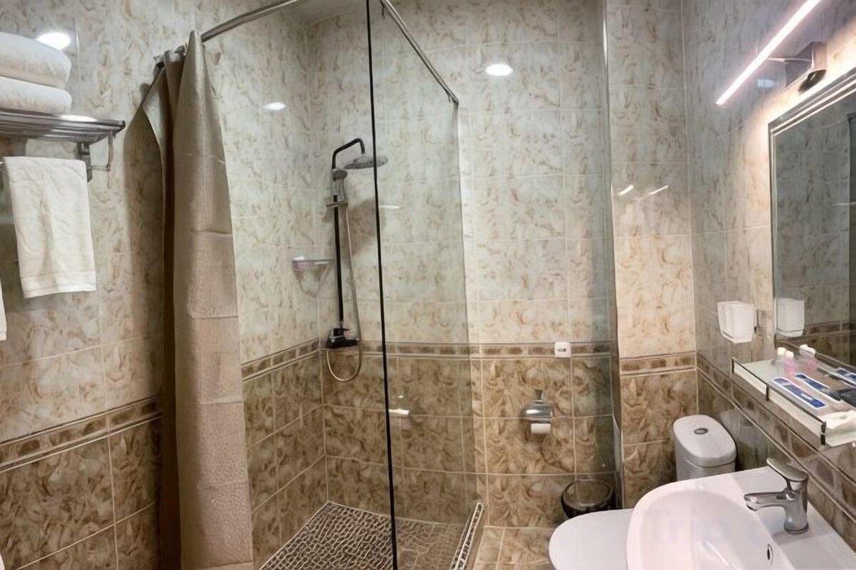 Moderni kylpyhuone, jossa on lasiseinällä varustettu suihku, wc ja pesuallas.