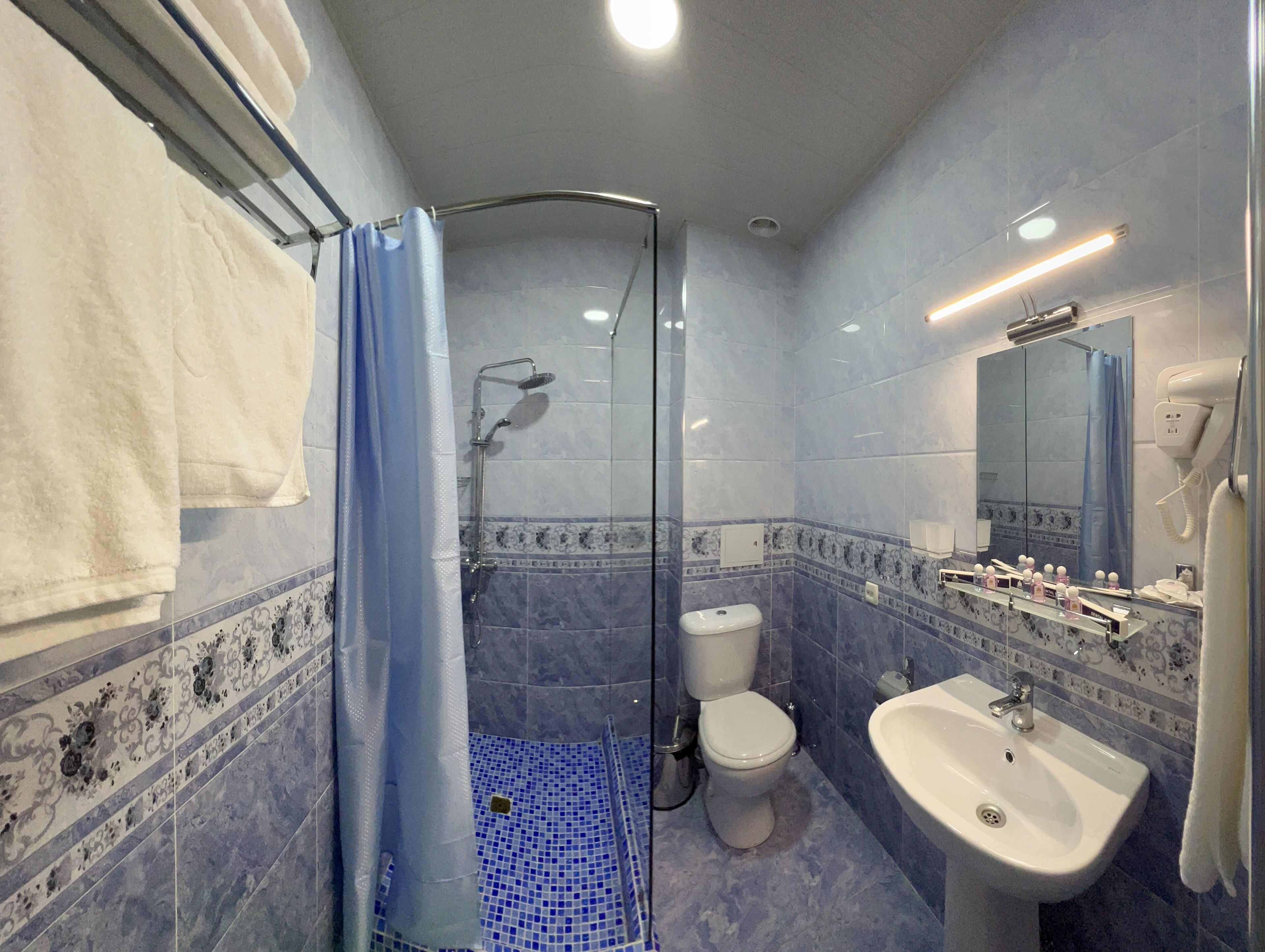 Une salle de bain avec une douche à parois de verre, un lavabo blanc et des toilettes.