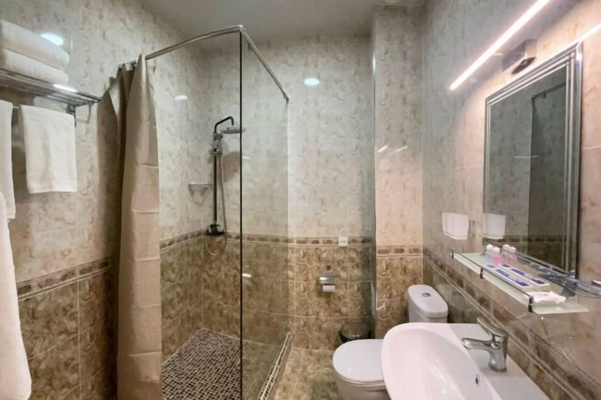 Un bagno con doccia vetro, lavabo bianco e WC.