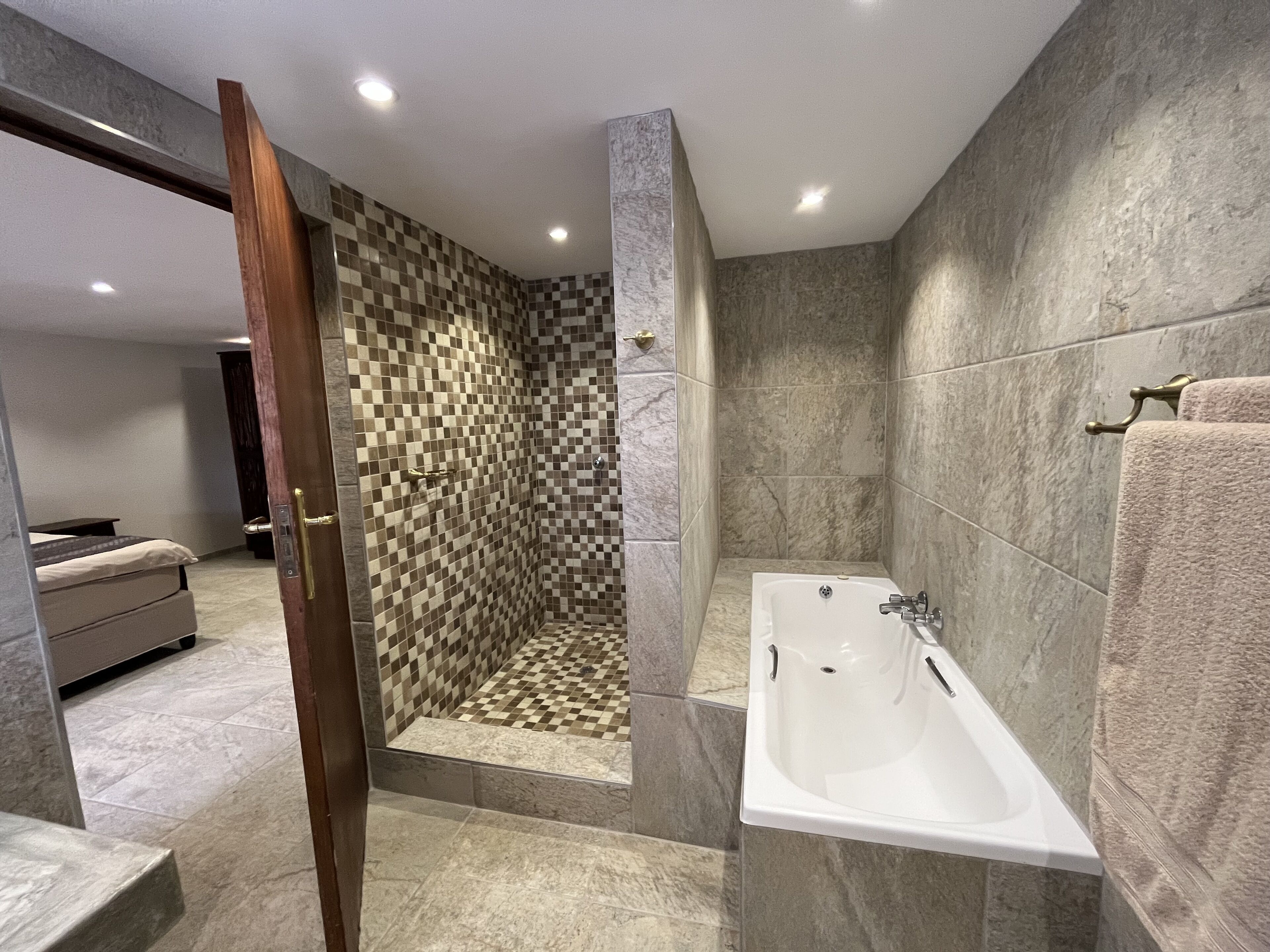 Un baño moderno con pared de ducha a cuadros, una bañera independiente y un lavamanos a la vista.
