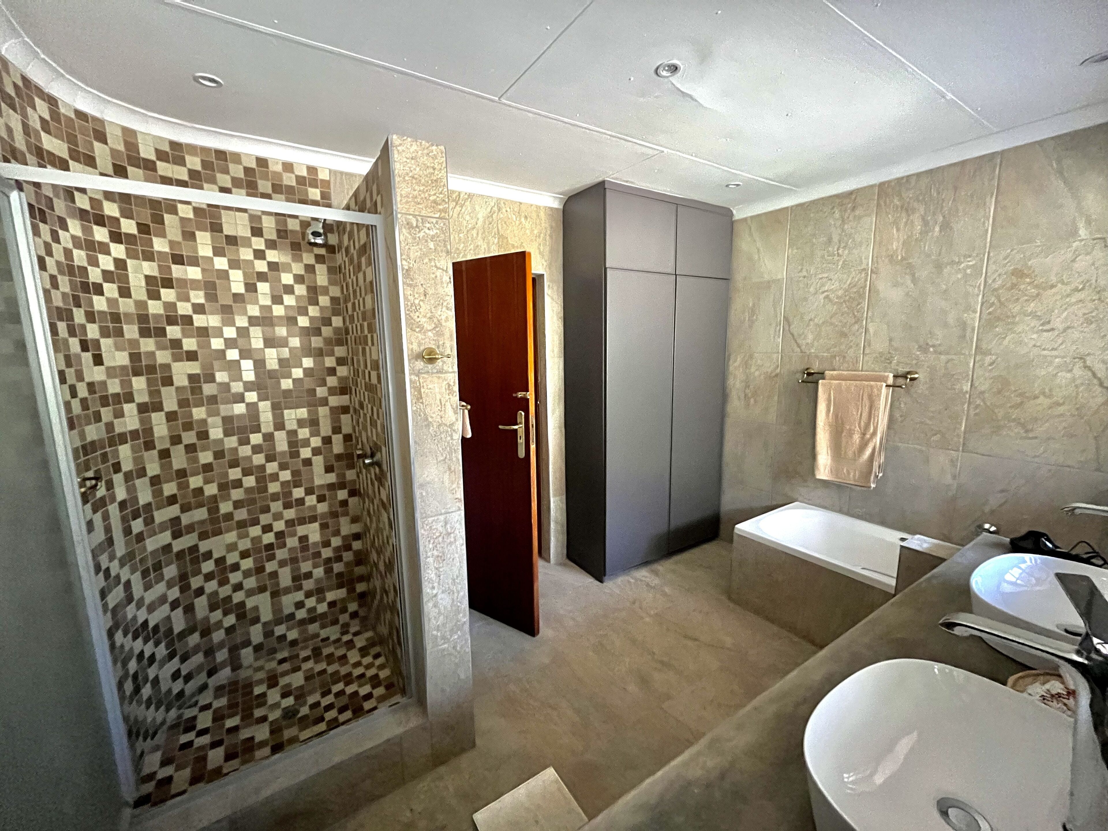 A modern bathroom with a shower, a bathtub, and a sink.