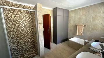 A modern bathroom with a shower, a bathtub, and a sink.
