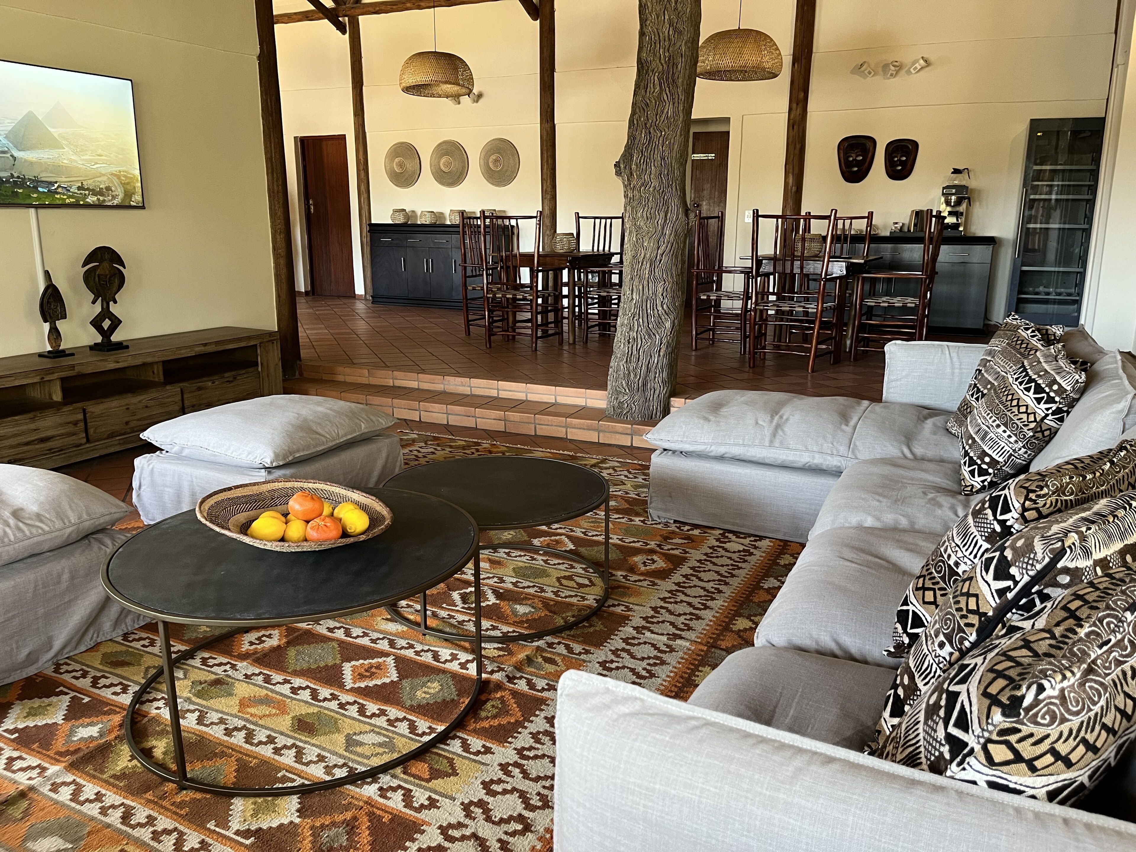 A spacious living area with a large sofa, two round coffee tables, and a patterned rug.